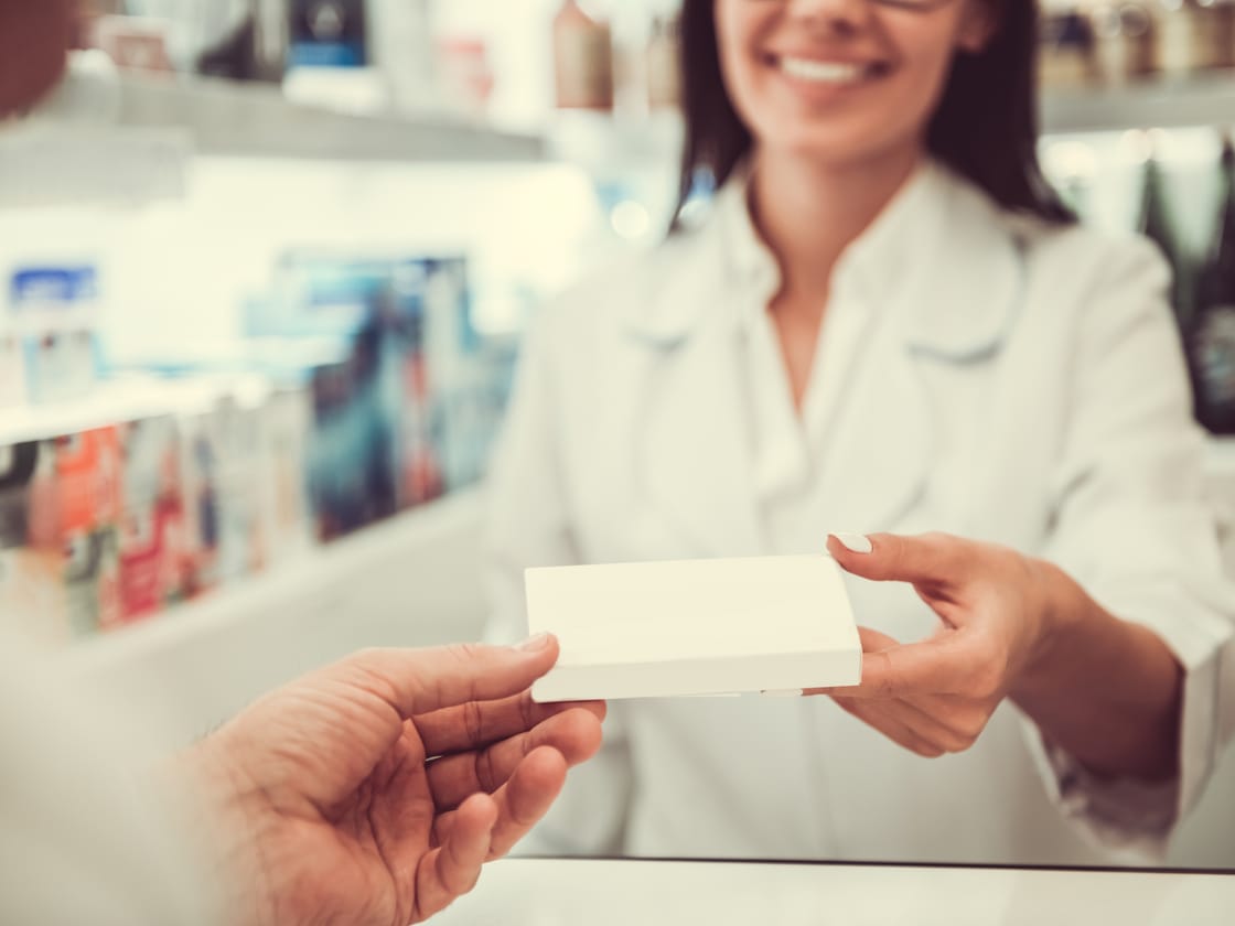 A smiling pharmacist at Somerset Park Pharmacy handing a prescription to a customer at the counter